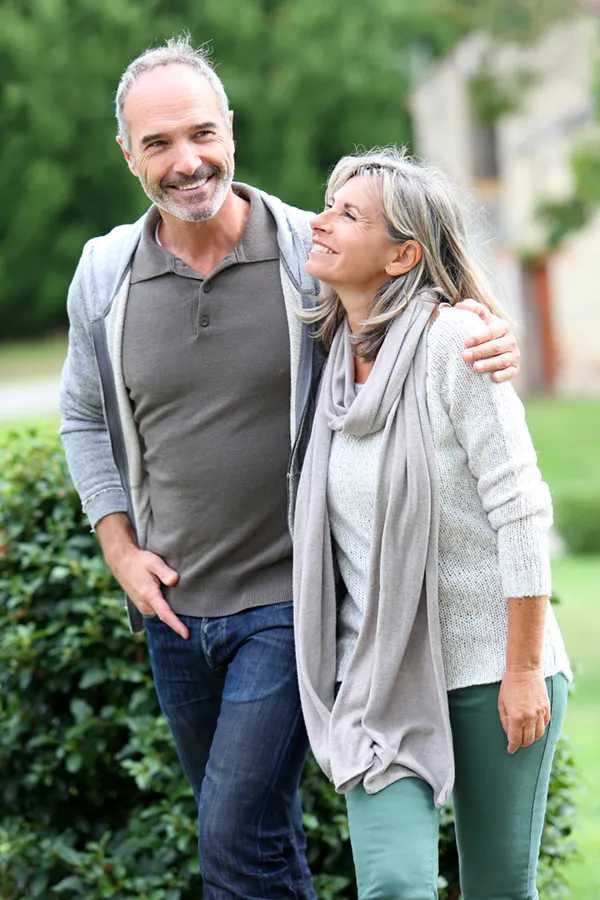 Bioidentical-Hormone-Therapy-Treatment A mature couple in gray toned clothes and jeans walk happily outside, happy with their successful bioidentical hormone treatments from Morgan Burns, APRN in Central Florida.