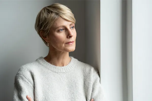 Chronic-Fatigue-Therapy A blond, middle-aged woman looks out the window with a tired expression. Get chronic fatigue treatment from Morgan Burns, APRN in Central Florida.