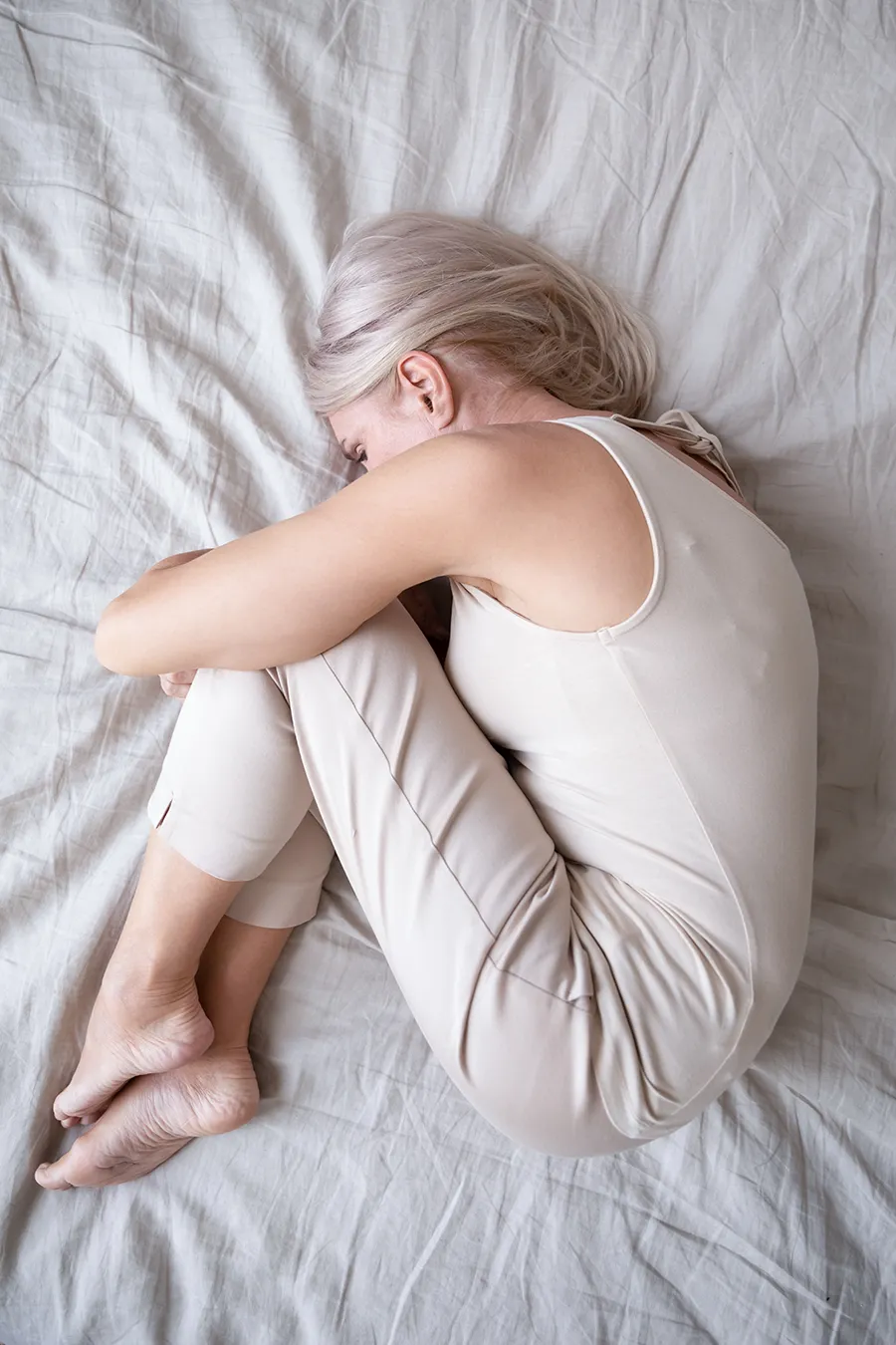 Depression-Treatment A woman curled up on a bed. Get depression treatment from Morgan Burns, APRN in Central Florida.
