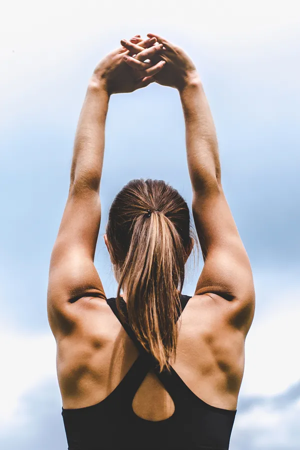 GLP-1-Weight-Loss-Injections-Treatment A toned woman seen from behind stretching her arms into the air. Get GLP-1 Weight Loss Injections from Morgan Burns, APRN in Central Florida.