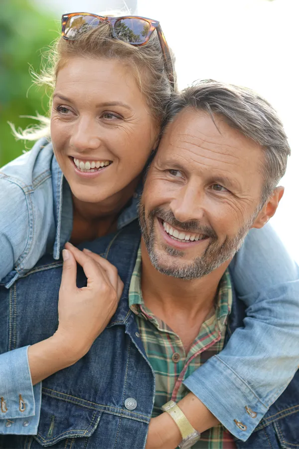 Hypogonadism-Treatment A couple in denim jackets embrace playfully outdoors. Get hypogonadism treatment from Morgan Burns, APRN in Central Florida.