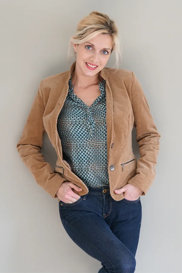 Metabolic-Syndrome-Treatment A smiling blonde woman in a tan leather jacket leans against a gray wall. Schedule metabolic syndrome from Morgan Burns, APRN in Central Florida.