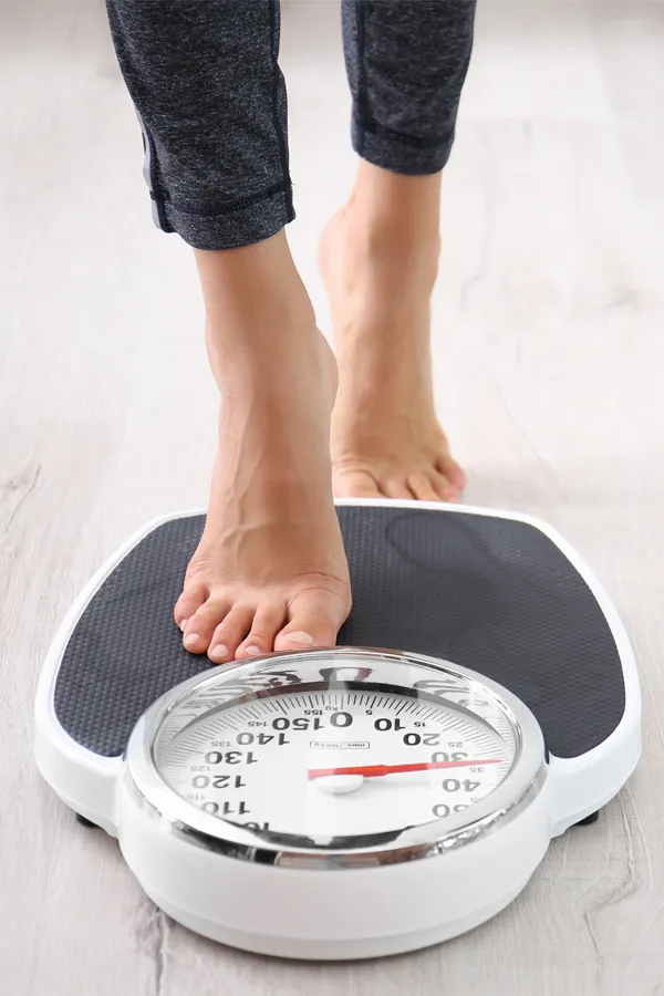 Obesity-Treatment Close up of feet stepping onto a scale. Receive expert functional medicine for obesity treatment by Morgan Burns, APRN in Central Florida.