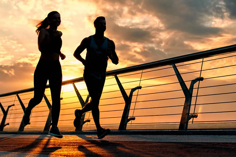 Performance-Enhancing-Peptides-Doctor A couple jogging on a bridge at sunrise, representing performance enhancing peptide therapy from Morgan Burns, APRN in Central Florida.
