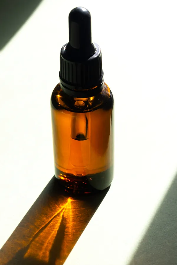 Performance-Enhancing-Peptides-Treatment A brown dropper bottle on a table lit by sunlight, representing performance enhancing peptide treatment from Morgan Burns, APRN in Central Florida.