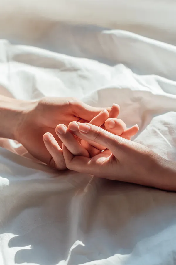 Sexual-Health-Peptide-Therapy-Treatment A close up of a man and woman's hands lightly clasping on a bedsheet, representing successful sexual health peptide therapy for men and women by Morgan Burns, APRN in Central Florida.