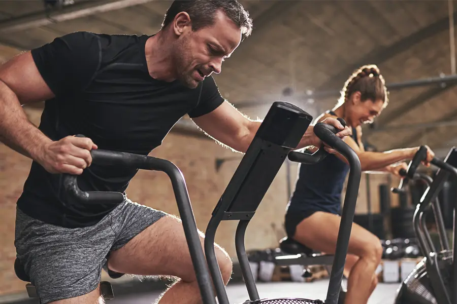 Tirzepatide-Doctor A couple in a brick gym work as hard as they can on exercise bikes, inspired by successful Tirzepatide treatment from Morgan Burns, APRN in Central Florida.
