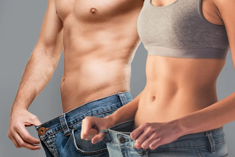 Weight-Loss-and-Metabolic-Reset-Clinic A man and a woman with toned bodies hold their jeans away from their waists to show weight loss. Get weight loss peptide treatment from Morgan Burns, APRN in Central Florida.