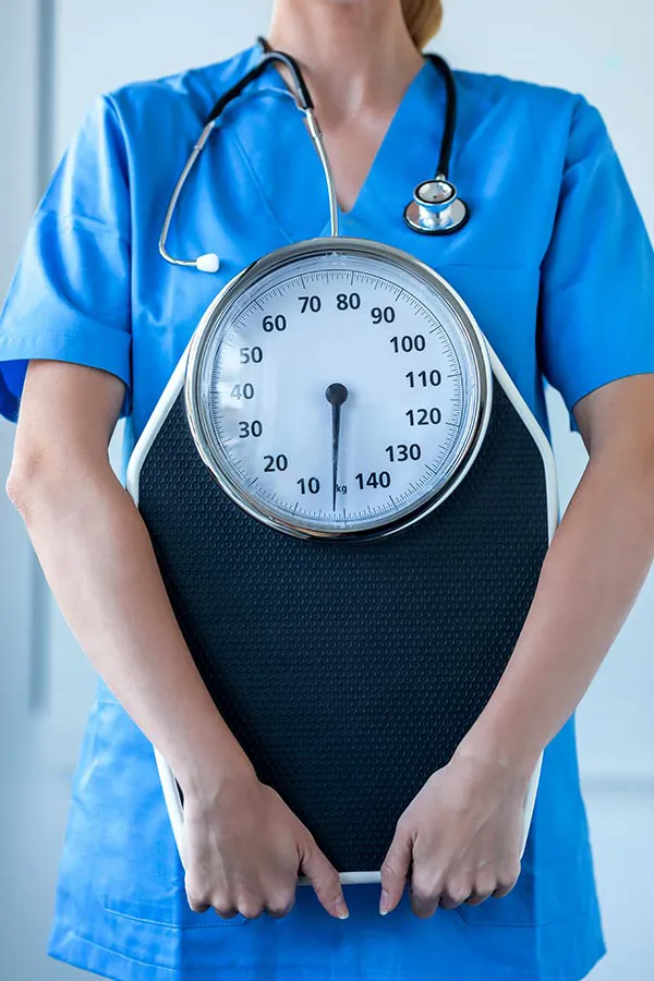 Weight-Management-Program-Treatment A clinician holds a scale. Sign up for the weight management program with Morgan Burns, APRN in Central Florida.